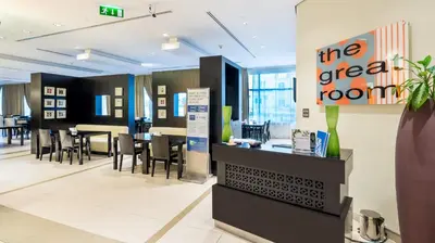 a restaurant with a counter and chairs and tables at Holiday Inn Express Dubai Internet City by IHG in Dubai