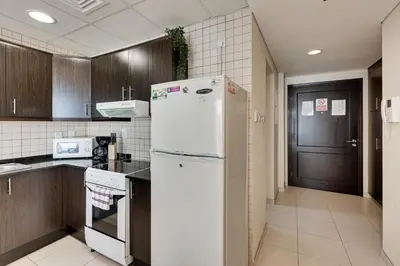 a kitchen with a white refrigerator and a black door at Sea View Studio 10min from beach Royal Oceanic in Dubai