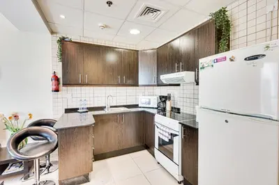 a kitchen with wooden cabinets and a white refrigerator at Sea View Studio 10min from beach Royal Oceanic in Dubai