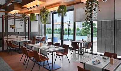 a restaurant with tables and chairs and large windows at Barcelo Business Bay Dubai in Dubai