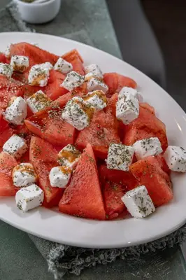 a plate of watermelon with fetzos and cheese on it at Element Al Jaddaf, Dubai in Dubai