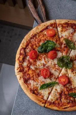a pizza with tomatoes and basil on a table at Element Al Jaddaf, Dubai in Dubai