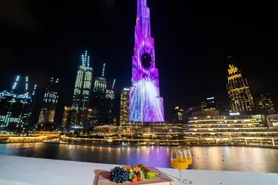 a table with a plate of food and a glass of wine at Durrani Homes - Heaven On Earth- Burj Khalifa Fireworks in Dubai