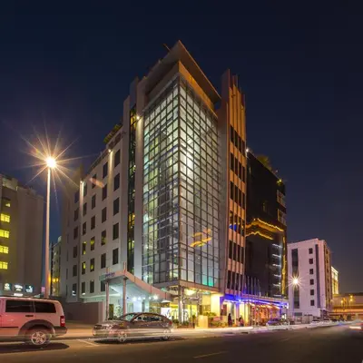 a large glass building with cars parked in front of it at MENA ApartHotel Albarsha At The Mall in Dubai