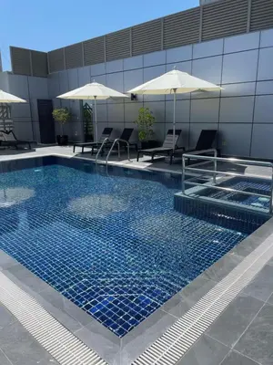a swimming pool with chairs and umbrellas in a building at MENA ApartHotel Albarsha At The Mall in Dubai