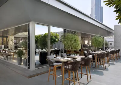 a restaurant with tables and chairs in front of a building at Fashion Avenue Dubai Mall-Burj Khalifa by The SHH in Dubai