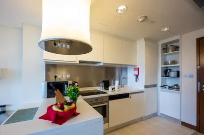 a kitchen with white cabinets and a bowl of fruit on a counter at Fashion Avenue Dubai Mall-Burj Khalifa by The SHH in Dubai