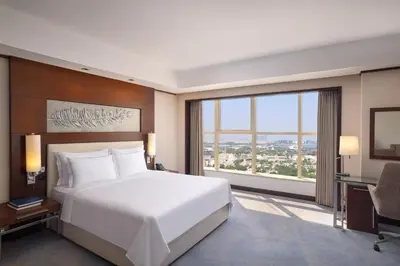 a bedroom with a large white bed and a desk at Grand Millennium Dubai in Dubai