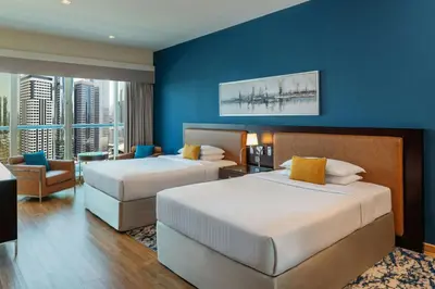 two beds in a hotel room with a blue wall at Four Points by Sheraton Sheikh Zayed Road in Dubai