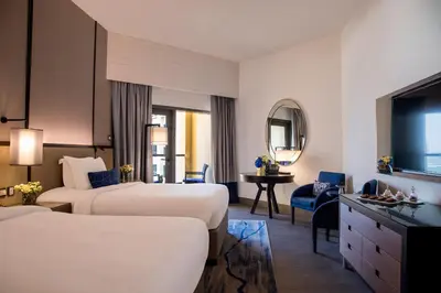 a hotel room with two beds and a mirror at Amwaj Rotana, Jumeirah Beach - Dubai in Dubai