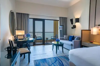 a hotel room with a bed and a living room at Amwaj Rotana, Jumeirah Beach - Dubai in Dubai