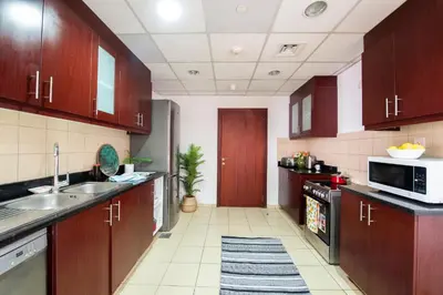 a large kitchen with wooden cabinets and a sink at Nasma Luxury Stays- Majestic Marina Views, Lavish 4BR Getaway in JBR in Dubai