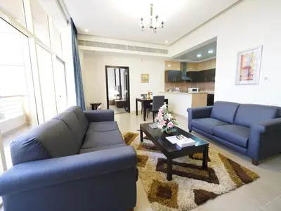 a living room with blue couches and a table at Skylark Hotel Apartments AL Barsha in Dubai
