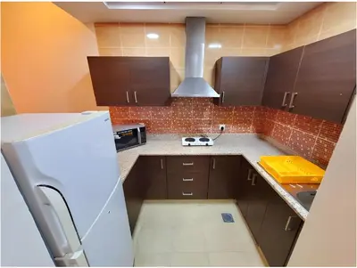 a kitchen with brown cabinets and a white refrigerator at Skylark Hotel Apartments AL Barsha in Dubai