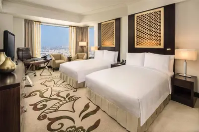 a hotel room with two beds and a desk at Conrad Dubai in Dubai