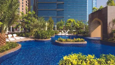 a swimming pool with blue water in a resort at Conrad Dubai in Dubai