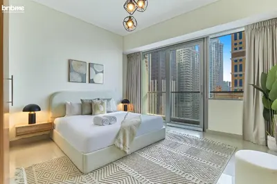 a white bedroom with a bed and a large window at bnbme - Dubai Marina 54th Floor Apt Sea View Two Balconies Pool Gym & Parking in Dubai
