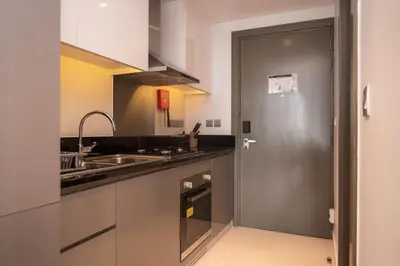 a kitchen with a sink and a silver door at Luton Vacation Homes - Damac Maison Prive Studio, Canal View, Dubai - 16AB03 in Dubai