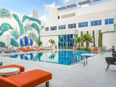 a hotel pool with orange chairs and a building at Novotel Dubai World Trade Centre in Dubai