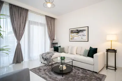 a white living room with a couch and a table at HiGuests - Chic Apt with Balcony and Pool near Burj Khalifa in Dubai