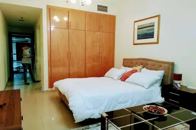 a bedroom with a large bed with a wooden cabinet at skynest homes studio in JLT in Dubai