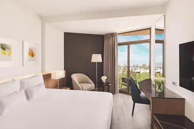 a hotel room with a bed and a desk and a window at JA Beach Hotel, Dubai in Dubai