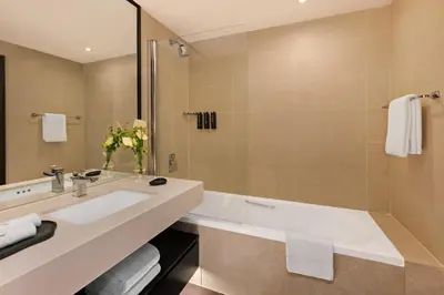 a bathroom with a tub and a sink and a mirror at JA Beach Hotel, Dubai in Dubai
