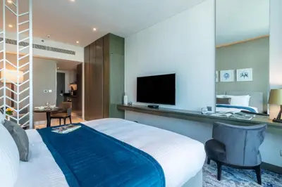a hotel room with a bed and a flat screen tv at The Smart Concierge - Damac Maison Prive in Dubai