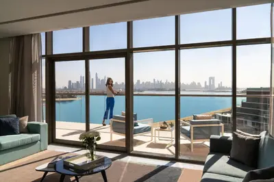 a woman standing in a living room looking out the window at Th8 Palm Dubai Beach Resort, Vignette Collection by IHG in Dubai