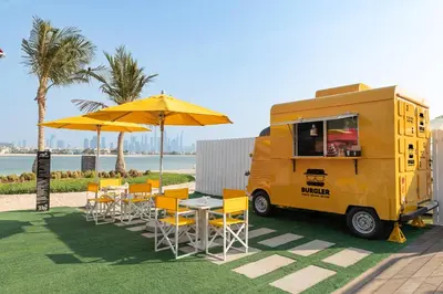 a yellow food truck parked next to a table and umbrella at Th8 Palm Dubai Beach Resort, Vignette Collection by IHG in Dubai