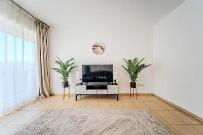 a living room with a television and two palm trees at Brand new Rimal 2BD in front of The JBR Beach in Dubai