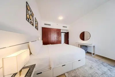 a white bedroom with a large bed and a mirror at Brand new Rimal 2BD in front of The JBR Beach in Dubai
