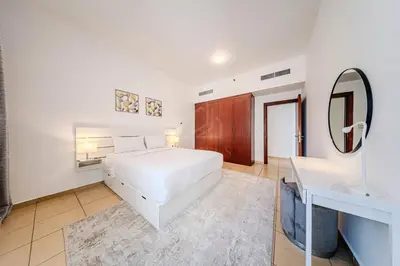 a white bedroom with a white bed and a mirror at Brand new Rimal 2BD in front of The JBR Beach in Dubai