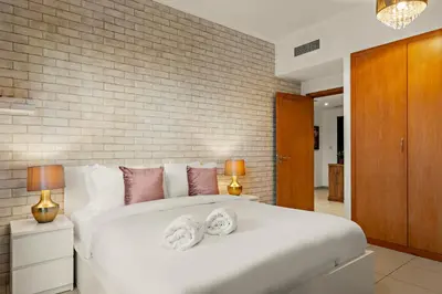 a bedroom with a white bed with two towels on it at FIRST CLASS 1BR Spectacular Fountain Views in Dubai