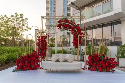 an arch with red flowers and a white couch at Radisson Dubai Damac Hills in Dubai