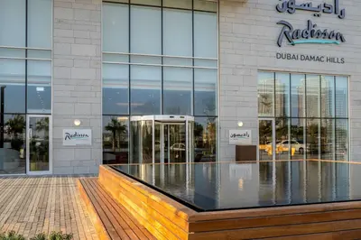 a building with a sign on the side of it at Radisson Dubai Damac Hills in Dubai