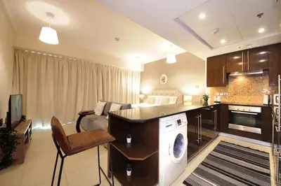a room with a bed and a kitchen with a washing machine at Prime Retreats - Downtown Dubai in Dubai