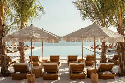 a group of chairs and umbrellas on a beach at The St. Regis Dubai, The Palm in Dubai