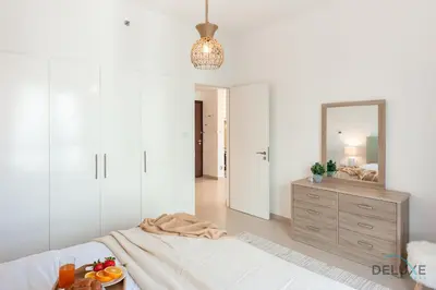 a white bedroom with a bed and a mirror at Blissful 1BR in Safi Town Square by Deluxe Holiday Homes in Dubai
