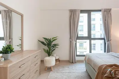 a bedroom with a bed and a dresser with a mirror at Blissful 1BR in Safi Town Square by Deluxe Holiday Homes in Dubai