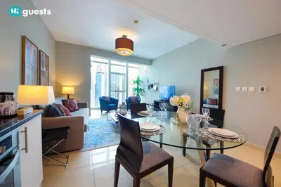 a living room with a glass table and chairs at HiGuests - Fabulous Duplex With Breathtaking Lake Views in Dubai