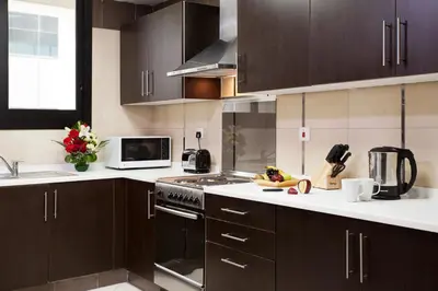 a kitchen with brown cabinets and a stove top oven at Al Waleed Holiday Homes in Dubai