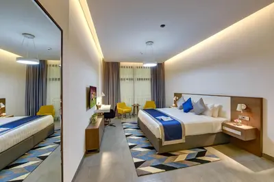 a hotel room with two beds and a desk at ABAR HOTEL APARTMENTS DIP-1 in Dubai