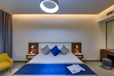 a bedroom with a large bed and a yellow chair at ABAR HOTEL APARTMENTS DIP-1 in Dubai