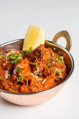 a bowl of curry with a spoon and a lime at ABAR HOTEL APARTMENTS DIP-1 in Dubai