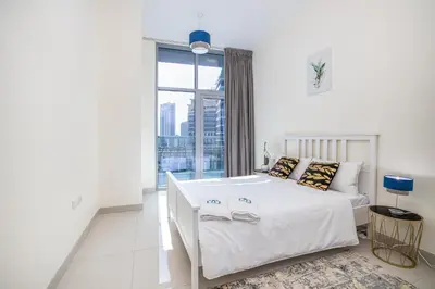 a white bedroom with a bed and a large window at Charming 3 BR with walking distance to the Beach in Dubai