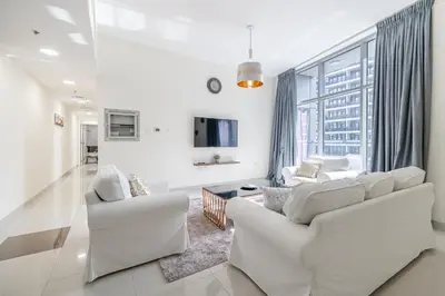 a living room with white furniture and a large window at Charming 3 BR with walking distance to the Beach in Dubai