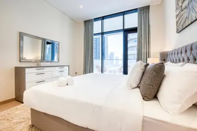 a bedroom with a large white bed with a large window at RH- Modern Comfort & bright 1BR near Dubai Mall, City Views in Dubai