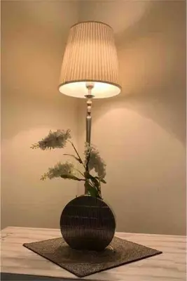 a lamp on a table with a vase with flowers at Balqis Residense Palm Jumeirah,Pool, Beach, Top floor, Full sea view, Restaurants in Dubai