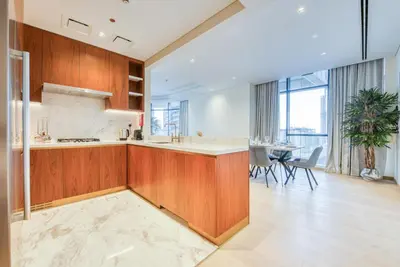 a kitchen with wooden cabinets and a dining room with a table at RH- Upscale Living in the Heart of the City, 02BR, Near Dubai Mall in Dubai